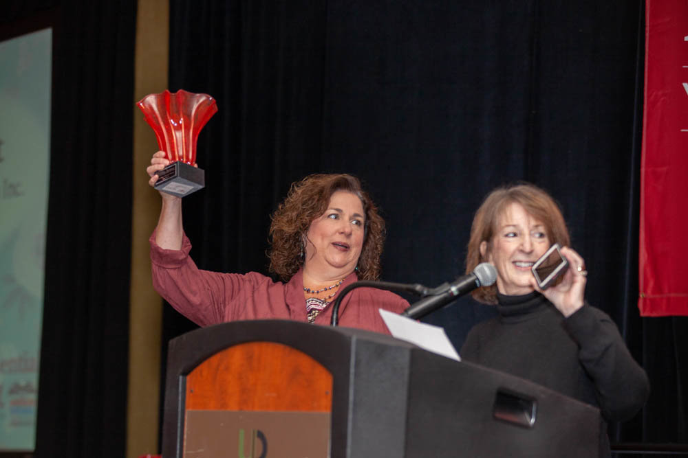 JUST A CALL AWAY
Springfield Business Journal Publisher Jennifer Jackson holds up an award for Drew Lewis Foundation founder Amy Blansit, who is on the phone with emcee Morey Mechlin during the Oct. 11 Most Influential Women luncheon. Blansit was unable to attend the event for her and 19 other women honored for their business, civic and philanthropic accomplishments. Nearly 400 people were on hand, and the event raised nearly $15,000 for its nonprofit partner, Women in Need.